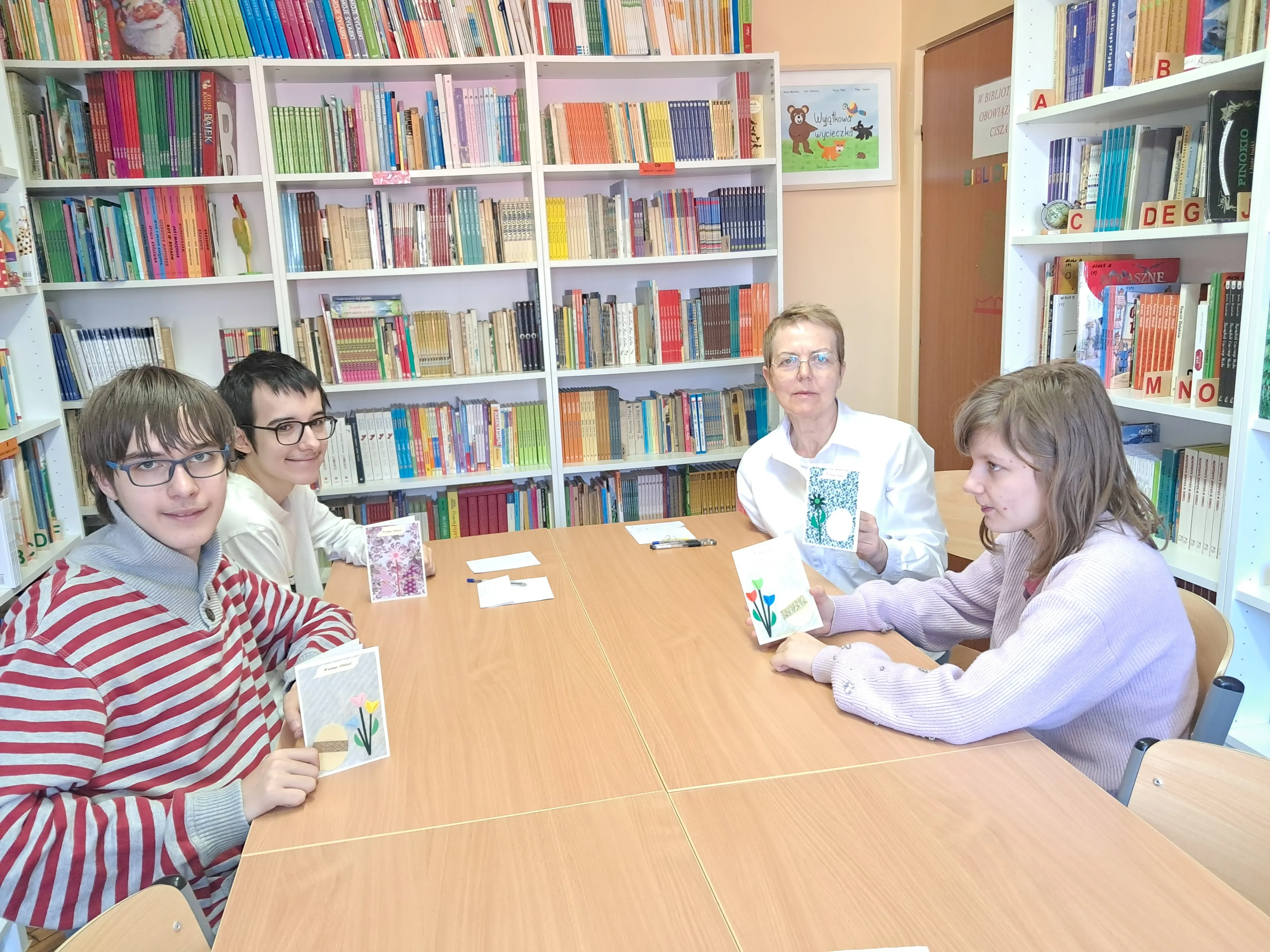 Uczniowie klasy 7b ( wraz z wychowawczynią ) w bibliotece szkolnej prezentują kartki świąteczne